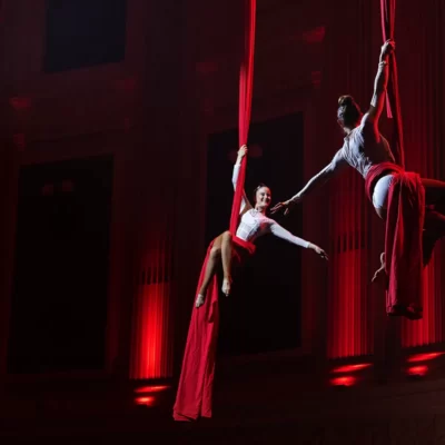 Two female aerial artist hanging from red material at an event in Brisbane City Hall