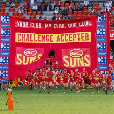 Gold Coast Suns running through banner on the field
