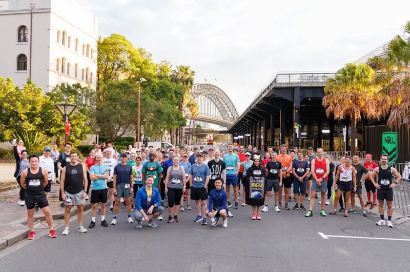 Group of people lining up for a charity run with the Sydney Harbour Bridge in the background
