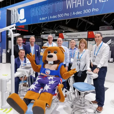World Dental Congress delegates pose with a mascot in a dentist chair