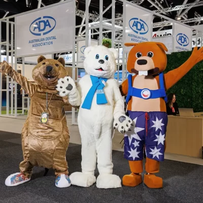 Three mascots pose in from of the ADA stand at the World Dental Congress at Sydney ICC